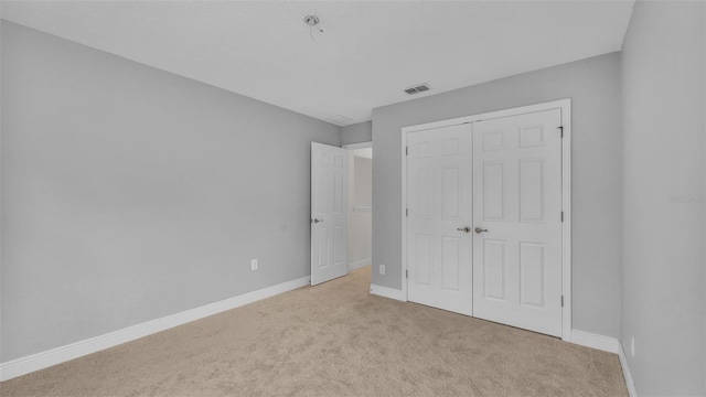 unfurnished bedroom with light carpet and a closet