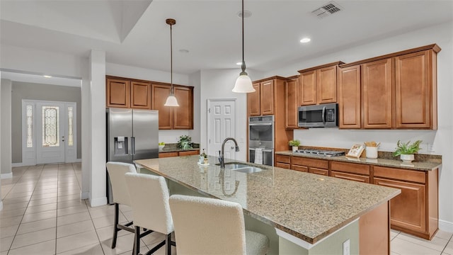 kitchen featuring sink, a center island with sink, light stone counters, and appliances with stainless steel finishes