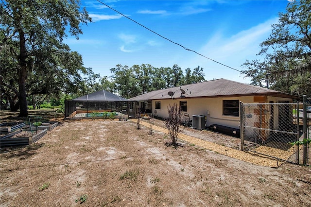 rear view of property with glass enclosure, a pool, and central AC