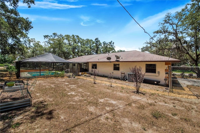 back of property featuring glass enclosure and central AC