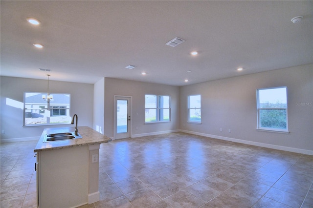 kitchen featuring pendant lighting, a wealth of natural light, a kitchen island with sink, and sink