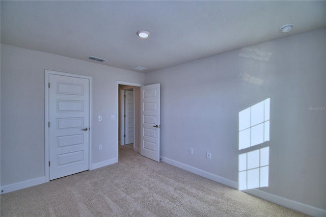 unfurnished bedroom with light carpet and a closet