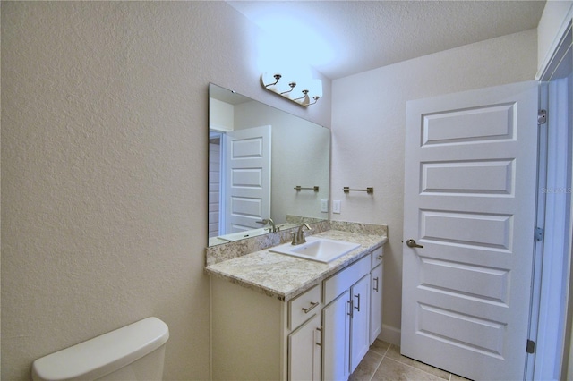 bathroom with toilet, a textured ceiling, vanity, and tile patterned floors