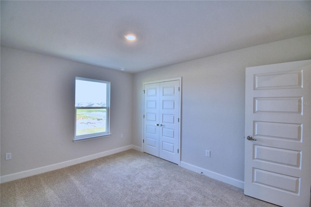 unfurnished bedroom with light colored carpet and a closet