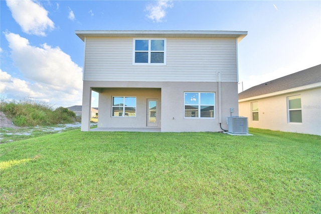 back of property with a lawn, a patio area, and central AC