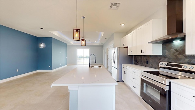 kitchen featuring sink, wall chimney range hood, decorative light fixtures, a center island with sink, and appliances with stainless steel finishes