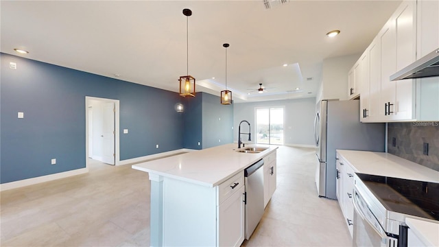 kitchen featuring white cabinets, sink, hanging light fixtures, ceiling fan, and an island with sink