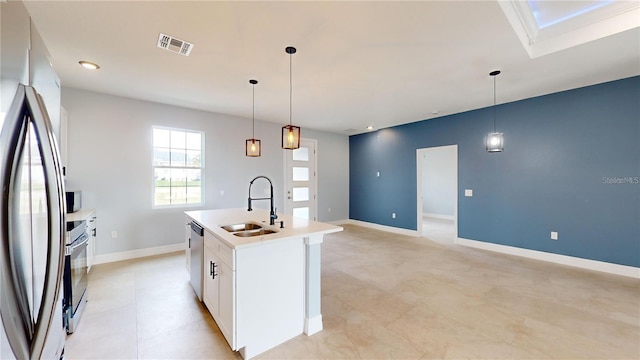 kitchen with appliances with stainless steel finishes, sink, pendant lighting, a center island with sink, and white cabinets