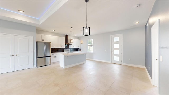 kitchen with stainless steel fridge, sink, a center island with sink, white cabinets, and hanging light fixtures