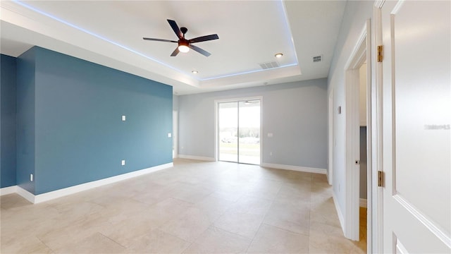 spare room with ceiling fan and a raised ceiling