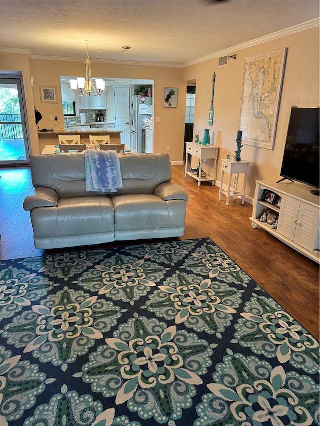 living room featuring hardwood / wood-style floors, crown molding, and an inviting chandelier