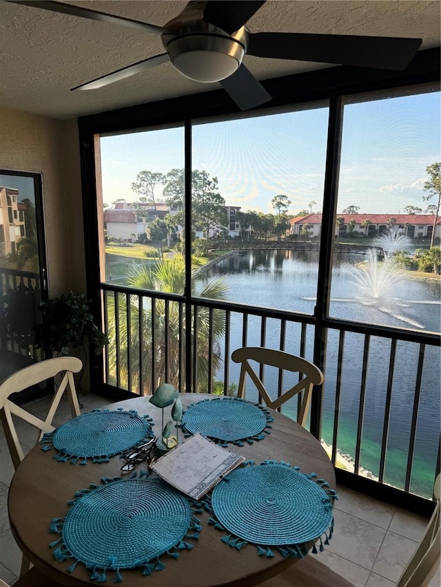 sunroom / solarium with a water view and ceiling fan