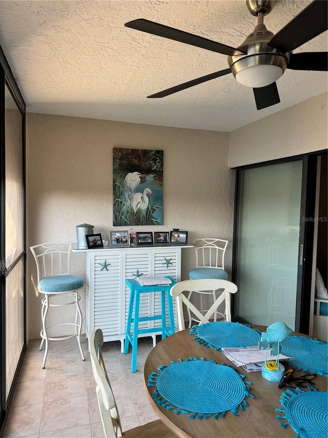 dining area with ceiling fan, tile patterned flooring, and a textured ceiling