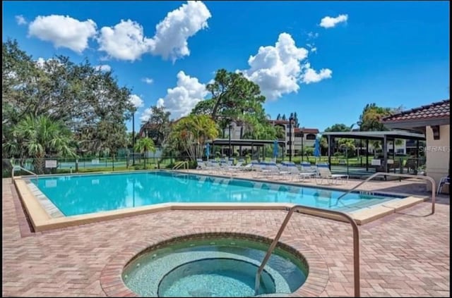 view of swimming pool featuring a patio and a hot tub