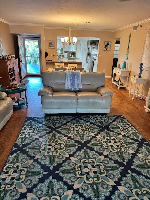 living room with a chandelier, wood-type flooring, a textured ceiling, and ornamental molding