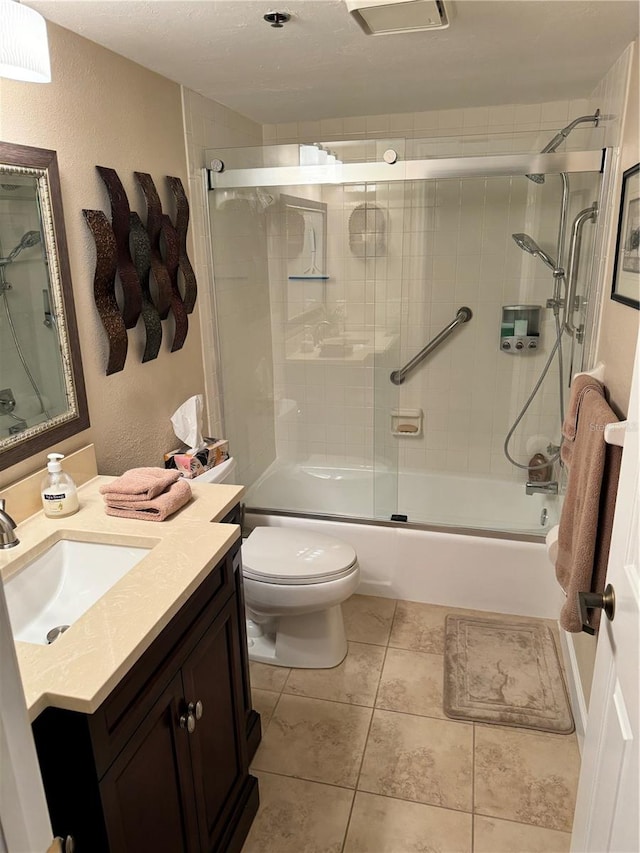 full bathroom featuring shower / bath combination with glass door, tile patterned flooring, vanity, and toilet