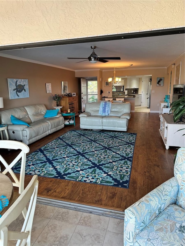 living room with ceiling fan with notable chandelier, hardwood / wood-style flooring, and crown molding