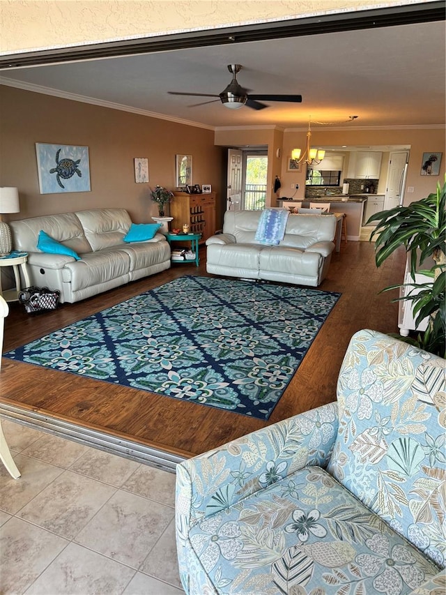 living room featuring ceiling fan with notable chandelier, light wood-type flooring, and ornamental molding