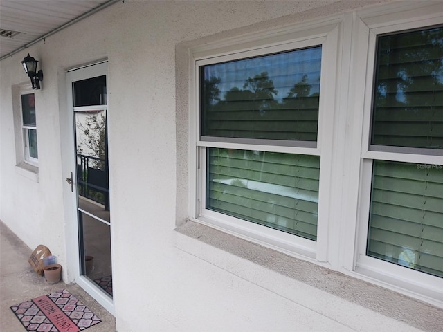 property entrance featuring visible vents and stucco siding