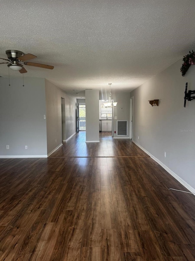 unfurnished living room with dark wood-style floors, baseboards, a textured ceiling, and ceiling fan with notable chandelier