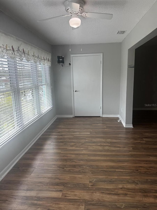 unfurnished dining area with dark wood-style floors, visible vents, ceiling fan, a textured ceiling, and baseboards