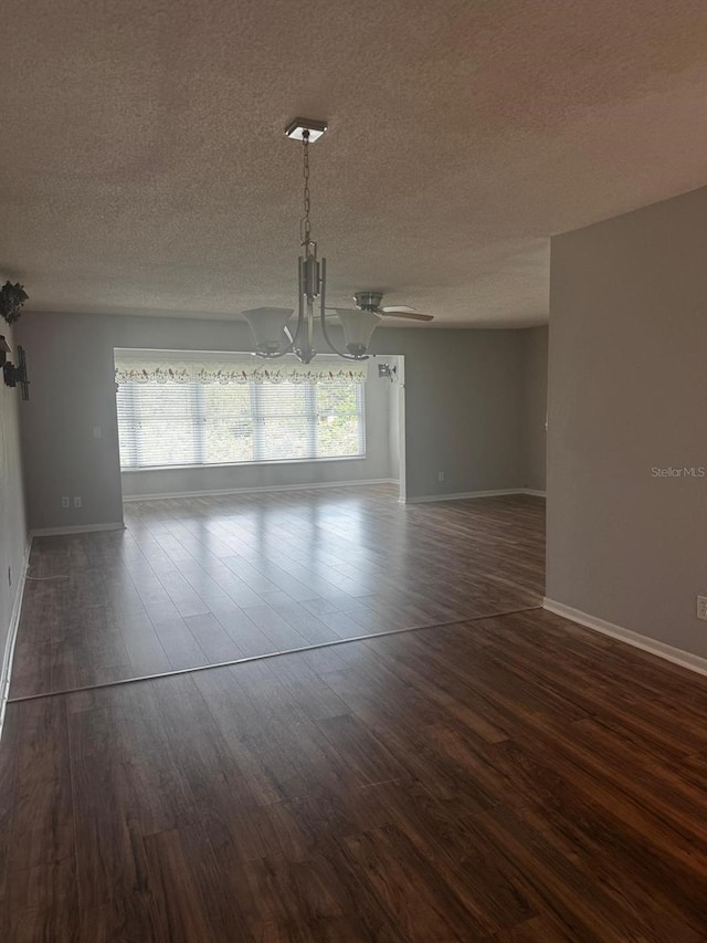 unfurnished dining area with plenty of natural light, a textured ceiling, a chandelier, and dark wood-style flooring