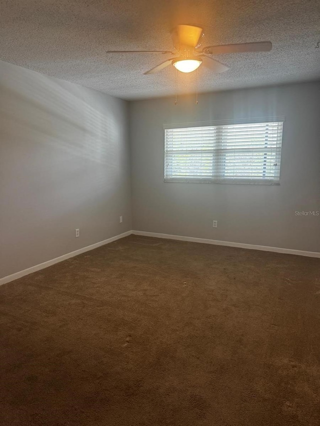 unfurnished room featuring dark colored carpet, ceiling fan, a textured ceiling, and baseboards