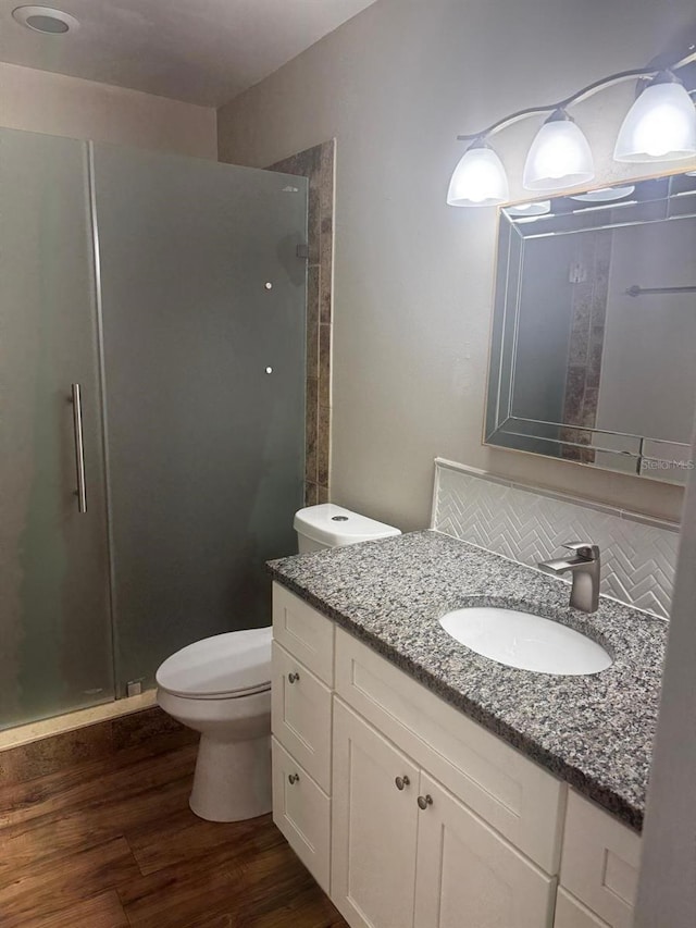 full bath featuring decorative backsplash, a shower stall, toilet, and wood finished floors