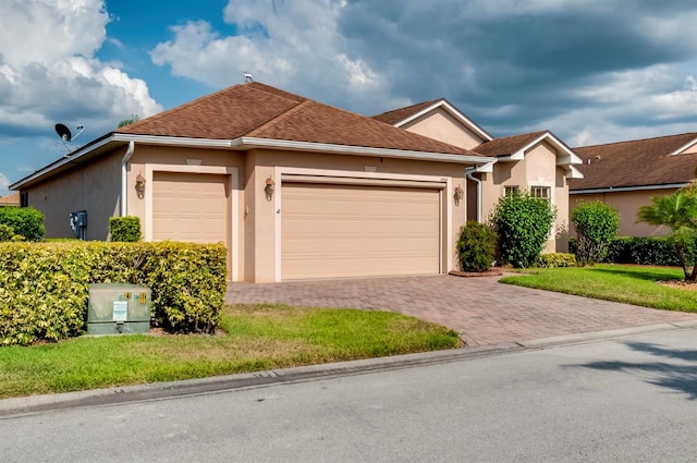 single story home with a front lawn, decorative driveway, an attached garage, and stucco siding