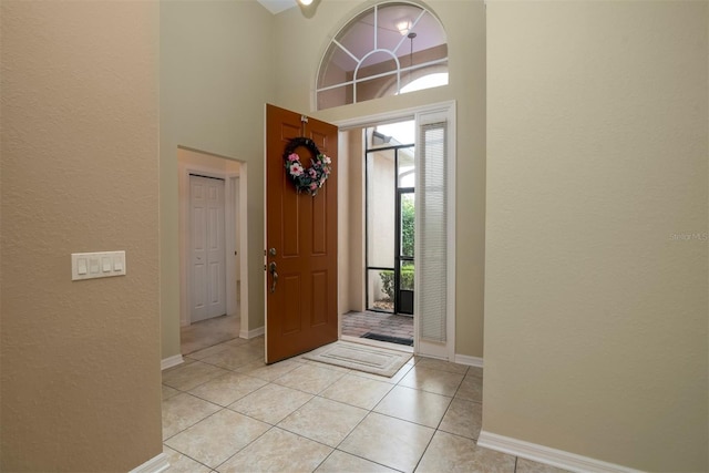 entrance foyer with light tile patterned floors and a towering ceiling