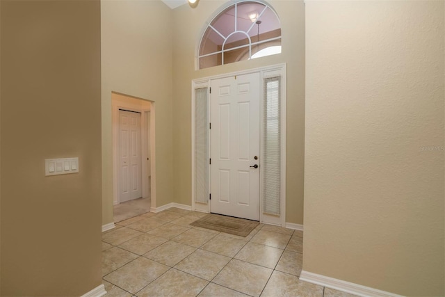 foyer entrance with light tile patterned floors and a towering ceiling