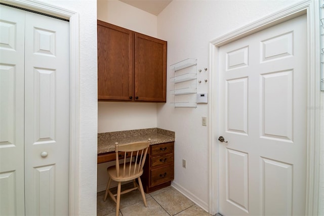 office with built in desk and light tile patterned flooring