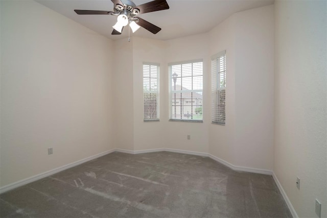 unfurnished room with dark colored carpet and ceiling fan