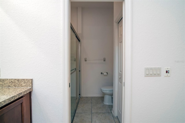 bathroom featuring toilet, vanity, tile patterned floors, and walk in shower