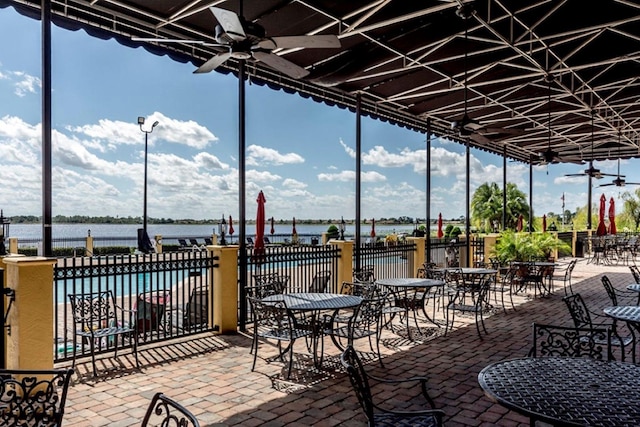 view of patio featuring a ceiling fan, a water view, fence, and a community pool