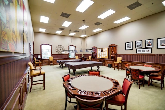 rec room with light carpet, a wainscoted wall, and a towering ceiling