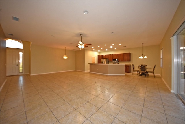 unfurnished living room featuring ceiling fan with notable chandelier and light tile patterned floors