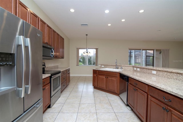 kitchen with hanging light fixtures, sink, light stone counters, and stainless steel appliances