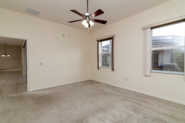 carpeted empty room featuring ceiling fan with notable chandelier