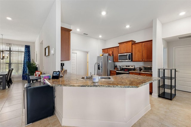 kitchen featuring light stone countertops, sink, kitchen peninsula, a kitchen bar, and appliances with stainless steel finishes