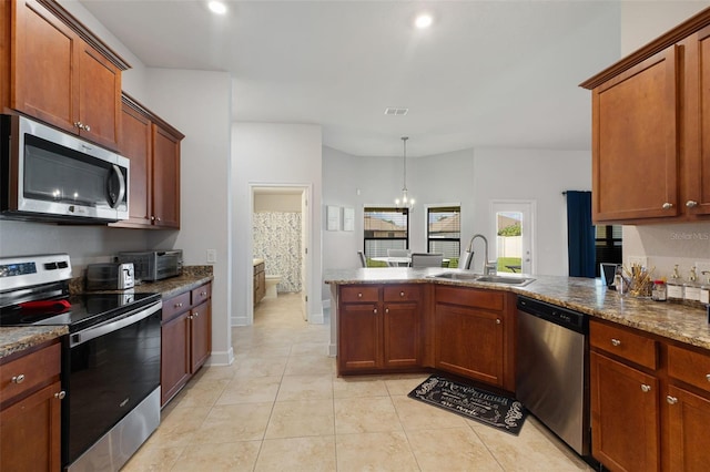 kitchen with sink, dark stone countertops, kitchen peninsula, stainless steel appliances, and a chandelier