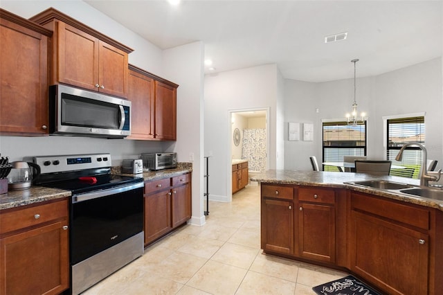 kitchen with appliances with stainless steel finishes, sink, light tile patterned floors, pendant lighting, and an inviting chandelier