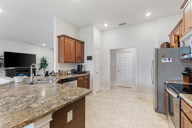 kitchen featuring dark stone countertops, sink, light tile patterned flooring, and appliances with stainless steel finishes