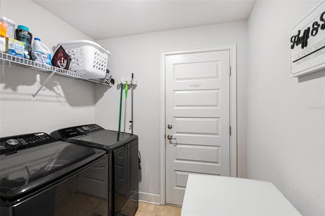 clothes washing area featuring light tile patterned flooring and washer and dryer