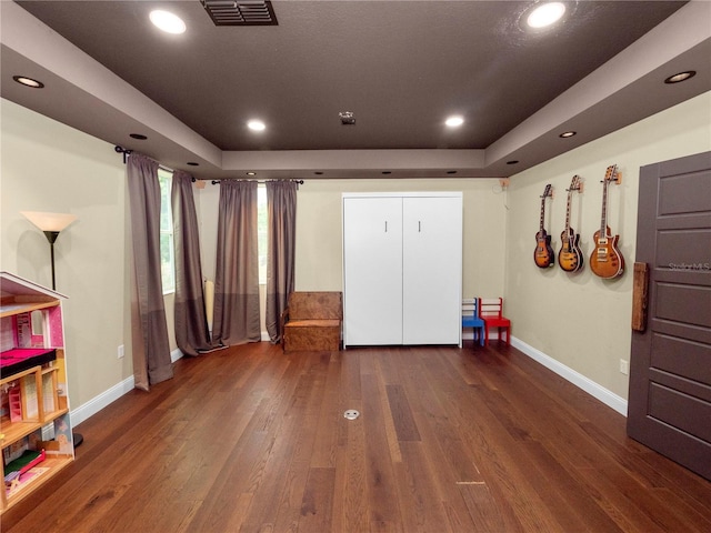 bedroom featuring a tray ceiling, wood finished floors, visible vents, and recessed lighting