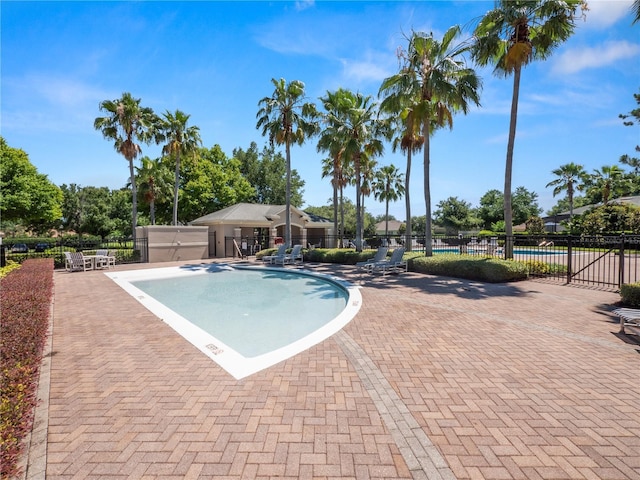 community pool with a patio area and fence