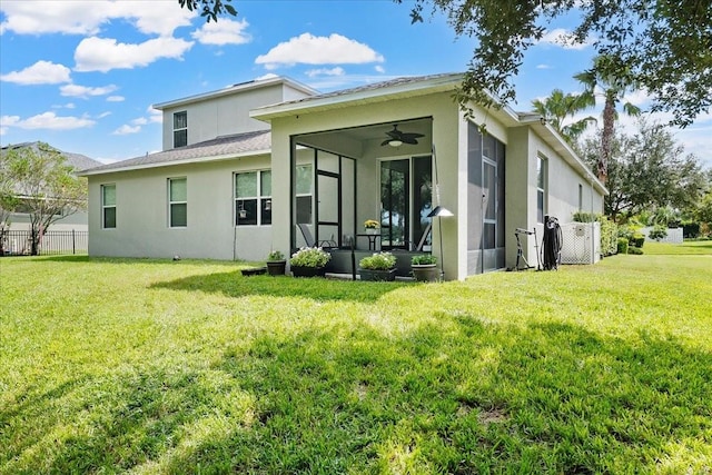 rear view of property with ceiling fan, fence, a sunroom, a yard, and stucco siding