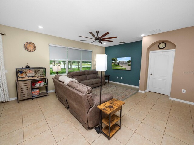 living area with light tile patterned floors, ceiling fan, and baseboards