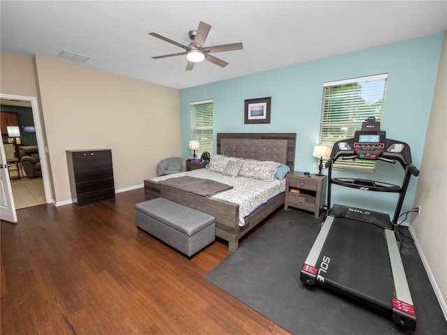 bedroom with a ceiling fan, baseboards, visible vents, and wood finished floors