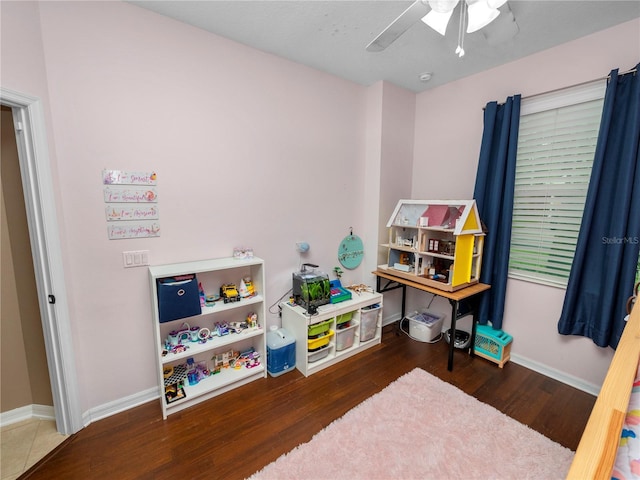 recreation room featuring a ceiling fan, baseboards, and wood finished floors